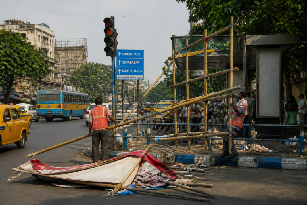 Kolkata puja advertising structures being removed from a roadside median by civic workers