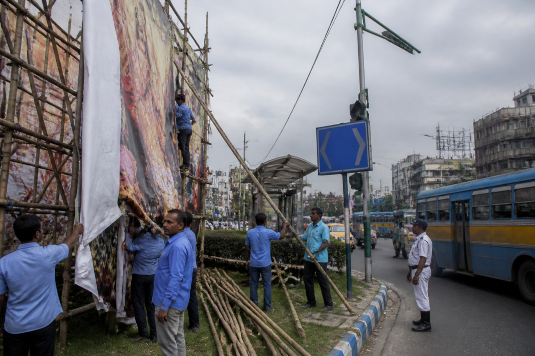 Kolkata puja advertising structures being removed from a city road near public infrastructure.