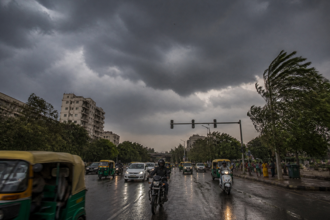 Delhi weather tomorrow forecast showing dark storm clouds over an urban road