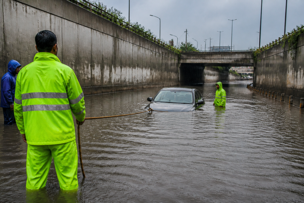 Flooded Sector 95 underpass in Noida after rain, with a car being pulled from deep water