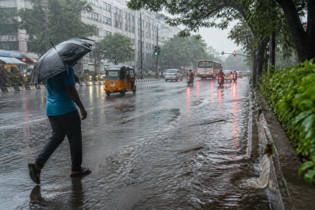 Tamil Nadu northeast monsoon rain over a Chennai street with wet roads and dark storm clouds